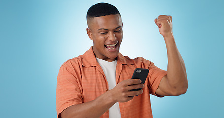 Image showing Man, phone and fist celebration in studio for trading profit, success or revenue by blue background. Investor, trader or person with smartphone for winning, prize or competition with online giveaway