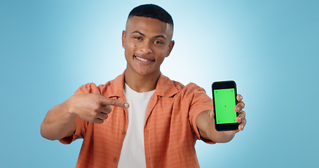 Image showing Man, portrait and point at phone, green screen and review of mobile app, promotion or choice by blue background. Person, smartphone and happy with mockup space, chromakey or feedback for ui in studio