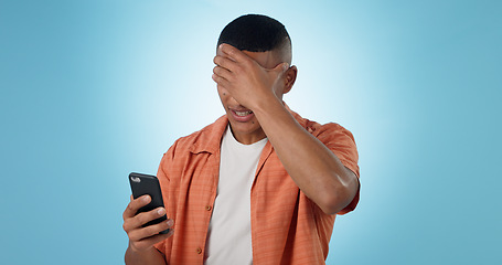 Image showing Man, phone and shock for bad news in studio for negative text message, disappointment or loss. Male person, mobile and connection or social media for unhappy discussion, blue background as mockup