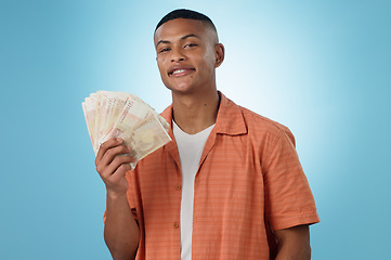 Image showing Young man, winner and money fan with success, bonus or winning in competition, college loan or cashback in studio. Portrait of student with cash, savings and scholarship funding on a blue background