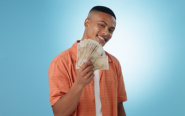 Image showing Happy man, winner and money fan with success, bonus or winning in competition, college loan or cashback in studio. Portrait of student with cash, savings and scholarship funding on a blue background