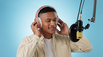 Image showing Artist man, headphones and mic in studio with thinking, ideas and creativity for song by blue background. Musician, person and microphone with recording, production and performance with singing voice