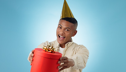 Image showing Happy man, party hat and gift for celebration in studio, blue background and portrait for mock up in Cape Town. Male model, present and bow for birthday, giveaway or event for reward, bonus or prize