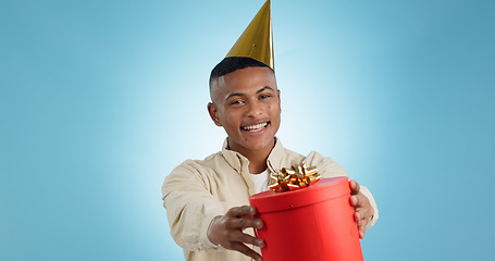 Image showing Portrait, happy man and party hat with gift in studio for celebration mock up on blue background in Cape Town. Model, giveaway and present for birthday, prize or event with competition, deal or offer