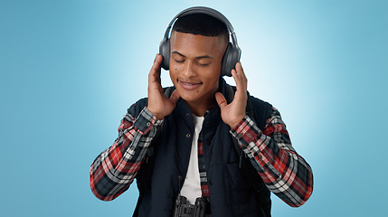 Image showing Happy, man and headphones in studio for music, podcast and relax with audio subscription on blue background. Smile, freedom and young model listening to sound, streaming multimedia and hearing radio