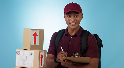 Image showing Delivery man, boxes and checklist for courier service, distribution and writing invoice on a blue background. Portrait of logistics worker with package, receipt and clipboard or paperwork in studio