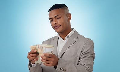 Image showing Business man, cash and money for financial investment, budget and trading, profit or counting his savings in studio. Young trader with decision or doubt for income, loan or salary on blue background