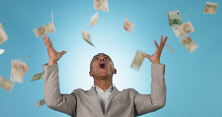 Image showing Business man, winner and money rain for success, celebration and lottery, bonus or financial freedom on a blue background. Excited worker or entrepreneur in studio with wow and yes for cash in air