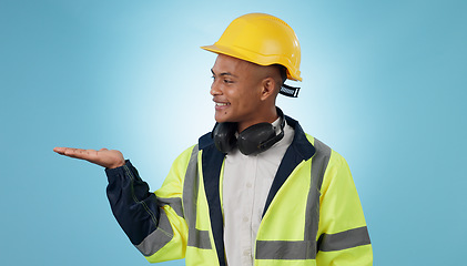 Image showing Construction worker, smile and with hand for advertising, promotion or mockup in blue background. Happy, face and builder show safety announcement, presentation or choice with space in studio