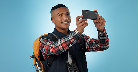 Image showing Hiking, man and smartphone with social media, photograph and travel on a studio background. Person, traveller and model with a cellphone, picture and post with blog, tourism and healthy with wellness