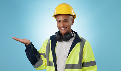 Image showing Happy, construction worker and portrait with hand advertising, promotion or mockup in blue background. Happy, face and builder show safety announcement, presentation or branding space in studio