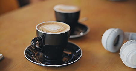 Image showing Coffee, notebook and headphones on table, closeup and breakfast for cappuccino, drink and matcha in diner. Cafe, restaurant and mug for latte, espresso and book with audio tech in morning in shop