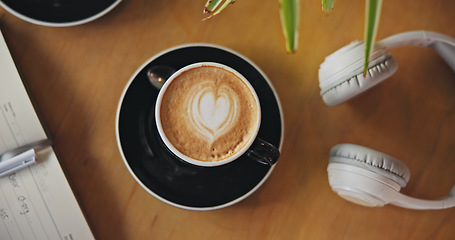 Image showing Coffee, notebook and headphones on table, top view and breakfast for cappuccino, drink and matcha in diner. Cafe, restaurant and latte with heart, espresso and book with audio tech in morning in shop