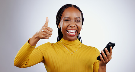 Image showing Phone, thumbs up and portrait of happy black woman in studio with review, feedback or vote on grey background. Success, emoji and face of lady model with thank you sign for smartphone, app or support