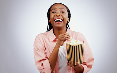 Image showing Portrait, laughing or black woman watching a movie in studio for cinema with popcorn to relax. Comedy, funny or happy African person eating snack for streaming film or subscription on grey background