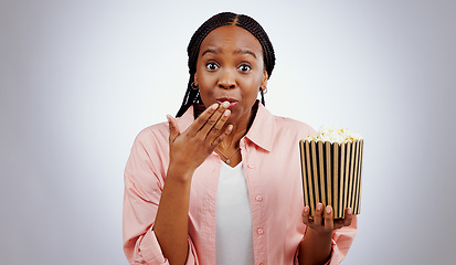 Image showing Portrait, surprise or black woman watching movie in studio for cinema with popcorn to relax. Omg, wow or shocked African person eating snack for streaming film or subscription on grey background