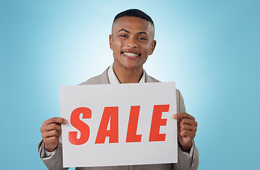 Image showing Portrait, sale sign or businessman by offer, discount deal or launch for poster advertising in studio. Happy, smile or manager with board for message, marketing or promotion card on blue background