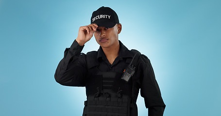 Image showing Security guard, confidence and man or employee in a studio with police and law enforcement. Blue background, surveillance and officer with hat and helping for safety and danger of bodyguard worker