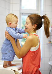 Image showing Mother, holding and baby for dressing in home on changing table for future, growth or development. Young woman, infant and playful in morning with smile of face for child, curiosity and motor skills