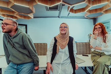 Image showing A group of young business professionals stands together, taking a well-deserved break from their busy workday, showcasing camaraderie, teamwork, and a moment of relaxation in their dynamic workplace