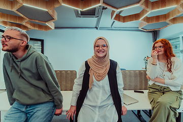 Image showing A group of young business professionals stands together, taking a well-deserved break from their busy workday, showcasing camaraderie, teamwork, and a moment of relaxation in their dynamic workplace