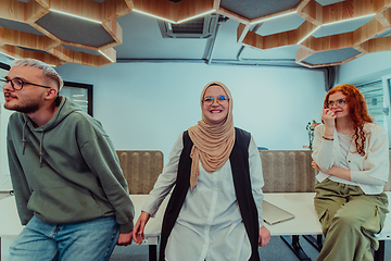 Image showing A group of young business professionals stands together, taking a well-deserved break from their busy workday, showcasing camaraderie, teamwork, and a moment of relaxation in their dynamic workplace