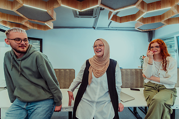 Image showing A group of young business professionals stands together, taking a well-deserved break from their busy workday, showcasing camaraderie, teamwork, and a moment of relaxation in their dynamic workplace