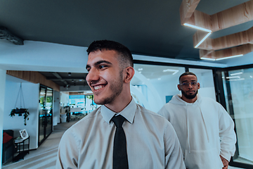 Image showing A group of young business professionals stands together, taking a well-deserved break from their busy workday, showcasing camaraderie, teamwork, and a moment of relaxation in their dynamic workplace