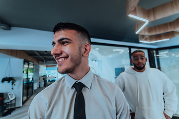 Image showing A group of young business professionals stands together, taking a well-deserved break from their busy workday, showcasing camaraderie, teamwork, and a moment of relaxation in their dynamic workplace