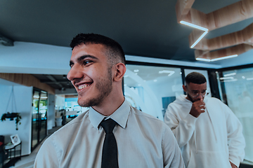 Image showing A group of young business professionals stands together, taking a well-deserved break from their busy workday, showcasing camaraderie, teamwork, and a moment of relaxation in their dynamic workplace