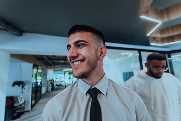 Image showing A group of young business professionals stands together, taking a well-deserved break from their busy workday, showcasing camaraderie, teamwork, and a moment of relaxation in their dynamic workplace