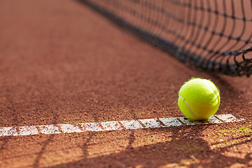 Image showing Tennis, ball and clay court, net and line for exercise, training and fitness outdoor in summer. Sports, netting and closeup of sphere on ground for game, competition and workout on field and pitch