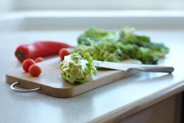 Image showing Chopping board, vegetables and knife on table in kitchen cooking organic food. Cutting wood, blade and plants on counter, lettuce and tomatoes, pepper and nutrition for healthy diet or salad in home