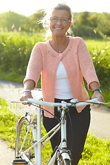 Image showing Portrait, smile and senior woman on bicycle outdoor, exercise and fitness in summer. Happy, elderly person on bike in nature or garden for cycling in countryside for body health, travel and glasses