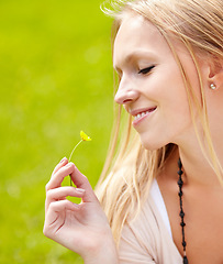 Image showing Woman, smile and smelling a flower in grass, garden or outdoor in field with growth in spring. Nature, happiness and person relax with daisy, blossom and peace in park, backyard or green meadow