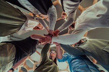 Image showing A group of young businessmen offer their hands together, symbolizing togetherness in the business world