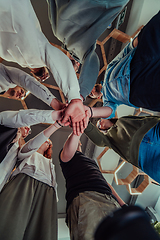 Image showing A group of young businessmen offer their hands together, symbolizing togetherness in the business world