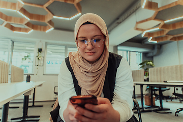 Image showing A businesswoman in a hijab using a smartphone in a modern office, epitomizing a successful and empowered professional in today's tech-savvy world