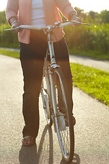 Image showing Nature, fitness and woman on a bicycle for exercise, workout and training on a street in park. Sports, health and closeup of female person cycling on a bike for an outdoor adventure in a garden.