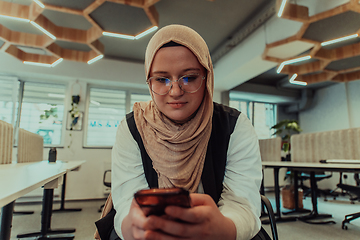 Image showing A businesswoman in a hijab using a smartphone in a modern office, epitomizing a successful and empowered professional in today's tech-savvy world