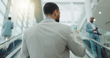 Image showing Businessman, phone and travel on escalator at airport for online booking, flight time or boarding. Rear view of man checking plane schedule on mobile smartphone for business trip on moving staircase