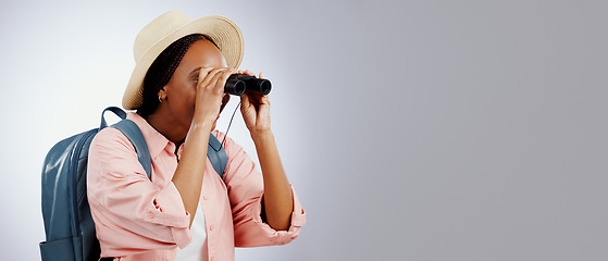 Image showing Woman, binoculars and explore on adventure, studio and travel or backpack by gray background. Black person, vacation and holiday in mockup, watch and search on journey, gear and equipment for tourist