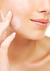 Image showing Woman, face and hand with cream in skincare, beauty or cosmetics against a studio background. Closeup of female person or model smile in satisfaction for lotion, creme or facial product and treatment