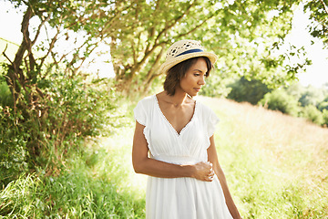 Image showing Woman, field and spring with hat, sunshine and thinking on walk in green nature for memory, relax and adventure. Girl, outdoor and ideas by trees, grass and freedom on countryside holiday in summer