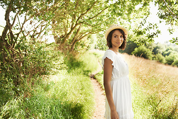 Image showing Portrait, smile and woman in the countryside on vacation, summer holiday and travel in woods. Happy person in dress, hat and nature outdoor at forest, garden field and grass path to relax in Brazil