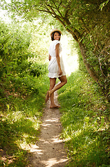 Image showing Portrait, smile and woman in hat in park in the countryside in summer, vacation and travel on holiday. Happy person in dress, woods and outdoor in nature at forest path, garden and field in Brazil