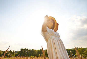 Image showing Thinking, relax and woman with sunshine, countryside and nature with grass, vacation and outdoor. Person, holiday and girl with lens flare, dress and sustainability with confidence, energy or freedom