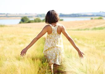 Image showing Back, freedom and woman at field in the countryside outdoor in summer. Rear view, person in nature and open arms at farm, grass or meadow and enjoy fresh air on vacation, holiday and travel to relax
