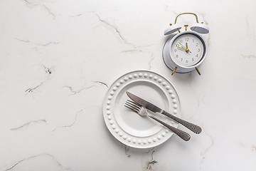 Image showing Concept of intermittent fasting, empty plate with clock