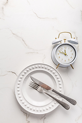 Image showing Concept of intermittent fasting, empty plate with clock